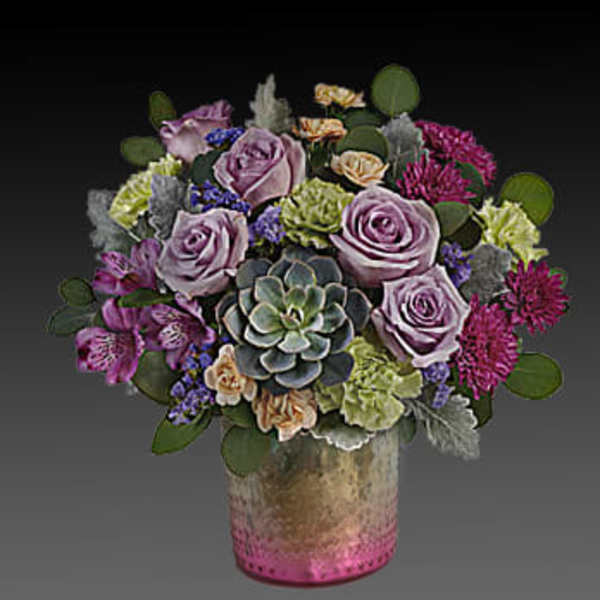 Lavender roses and succulents arranged in a pink vase