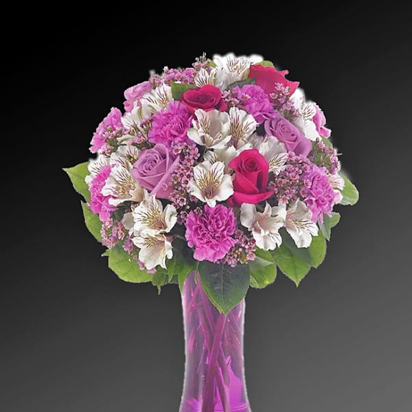 Pink and white mixed flower bouquet in a tall purple glass vase