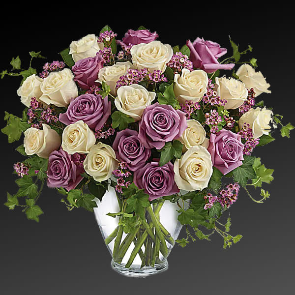 Bouquet of cream and lavender roses in a clear glass vase