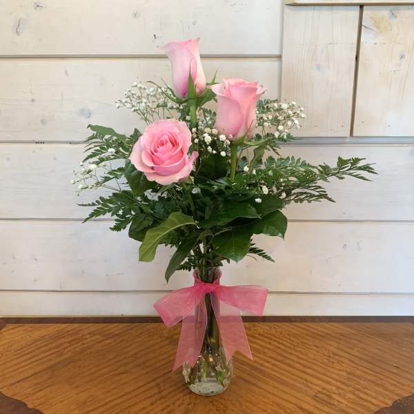 Pink roses in a clear glass vase with a pink ribbon