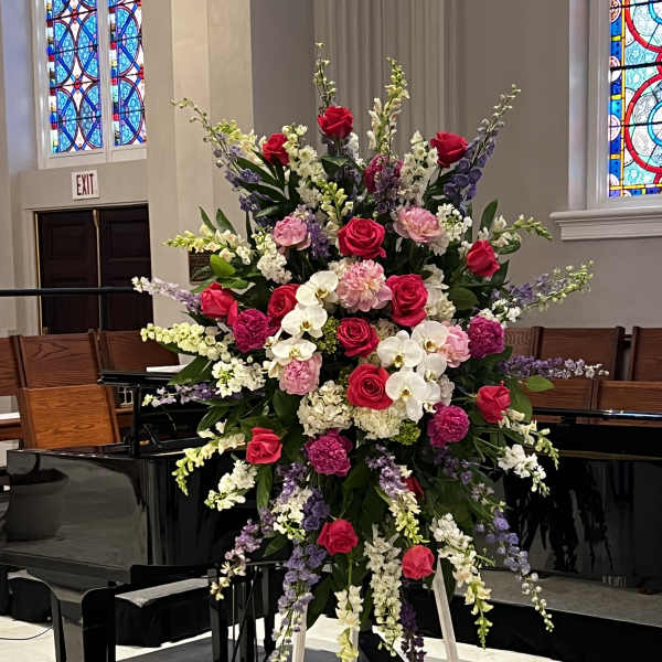 Large standing floral spray with pink roses, orchids, and lavender blooms