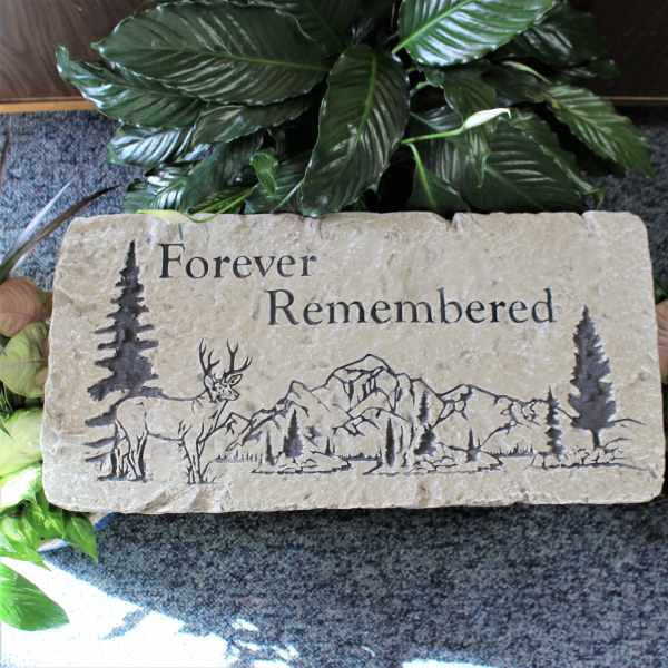 Stone memorial plaque engraved with a deer and mountains