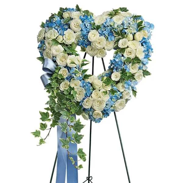 Heart-shaped floral wreath with white and blue flowers on a stand