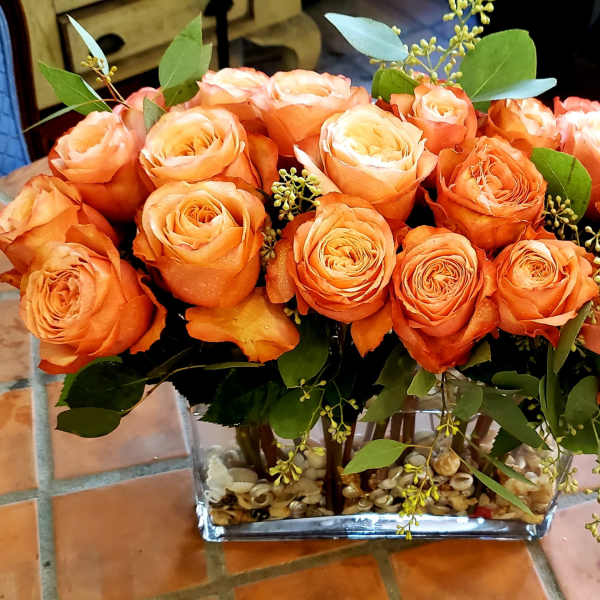 Orange roses arranged in a clear rectangular vase