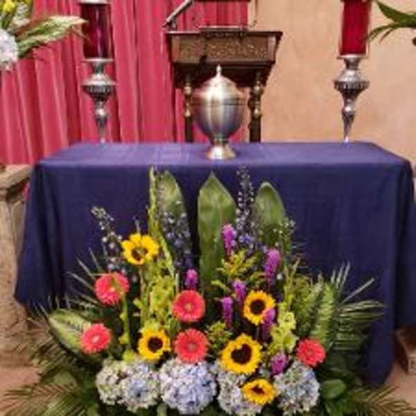 Colorful floral altar arrangement with sunflowers, gerbera daisies, and hydrangeas