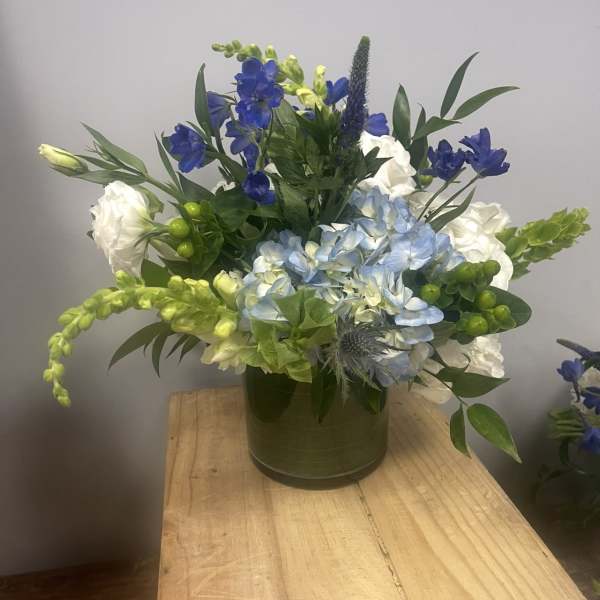 Blue and white floral arrangement in a green vase