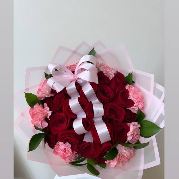 Bouquet of red roses and pink carnations with a pale pink ribbon