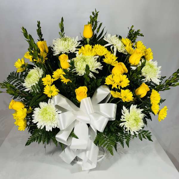 Yellow roses and white chrysanthemums arranged with a white ribbon bow