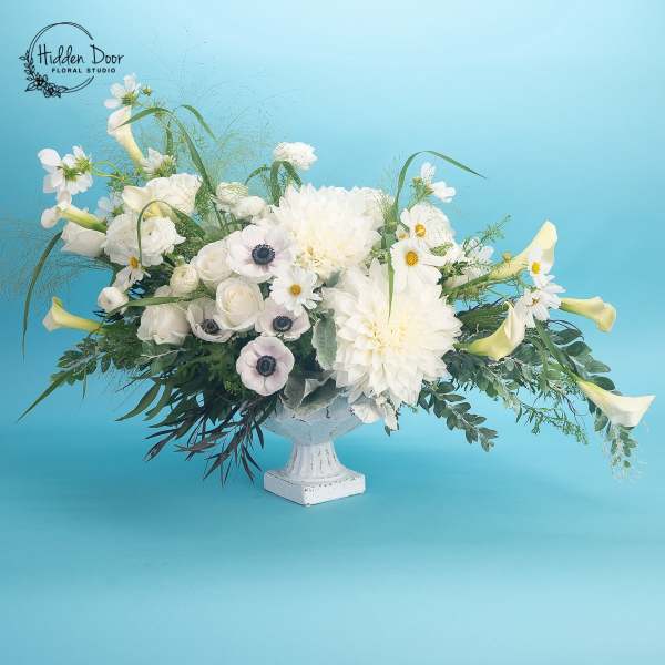 White floral arrangement in a white pedestal vase