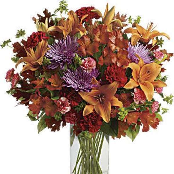 Autumn bouquet of lilies, chrysanthemums, and carnations in a clear glass vase