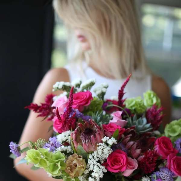 Handheld bouquet of pink roses and mixed blooms