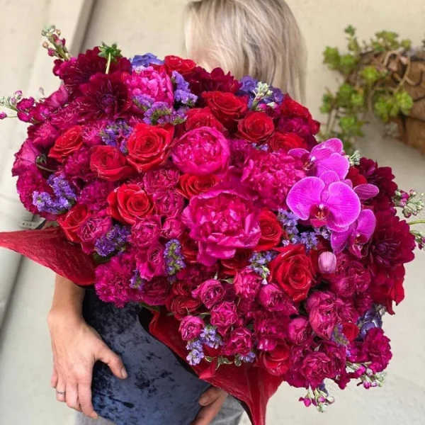 Large bouquet of red, pink, and purple flowers held by a person