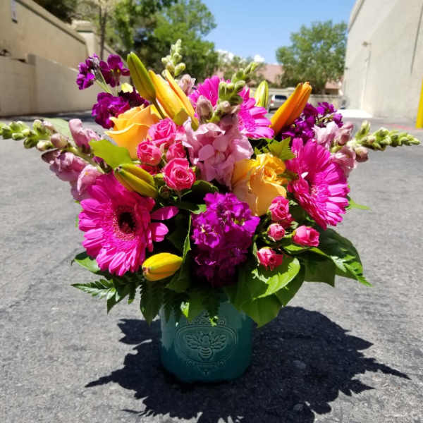 Bright mixed bouquet in a teal vase with pink, yellow, and purple flowers