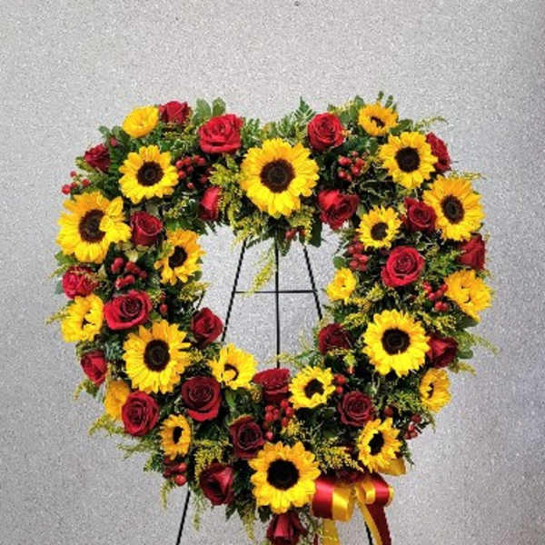 Heart-shaped wreath of sunflowers and red roses on a stand