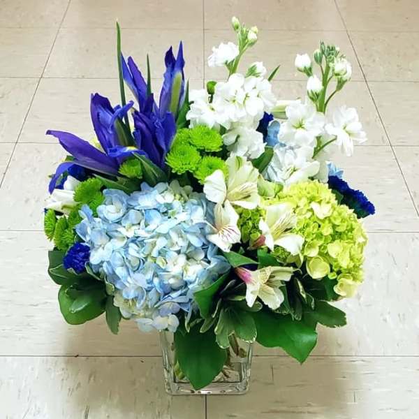 Blue and white floral arrangement in a clear square vase