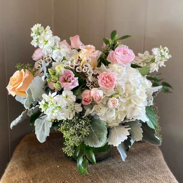 Mixed bouquet of pink and peach roses with white blooms in a glass vase