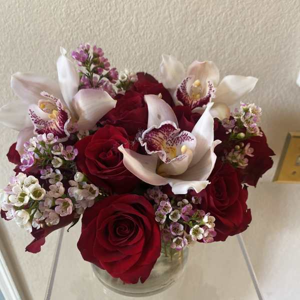 Red roses with white orchids in a clear glass vase