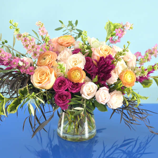 Mixed bouquet of peach, pink, and white flowers in a glass vase