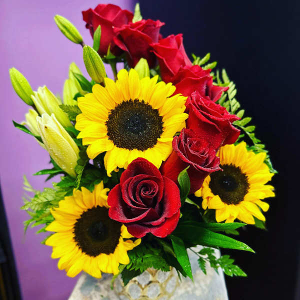 Bouquet of red roses and yellow sunflowers in a decorative vase