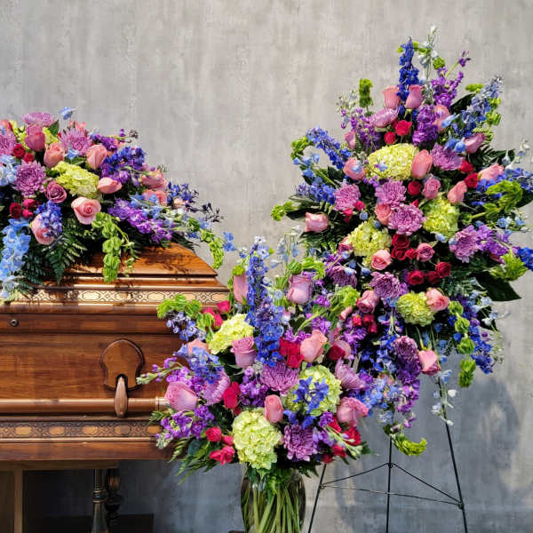 Large floral sprays on and beside a wooden casket