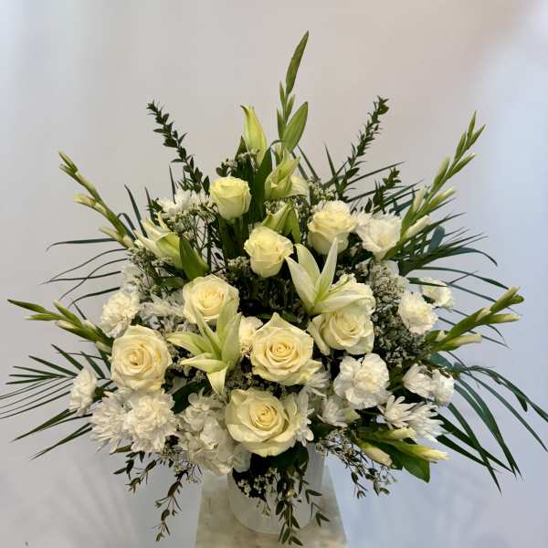 White roses and lilies arranged in a clear vase