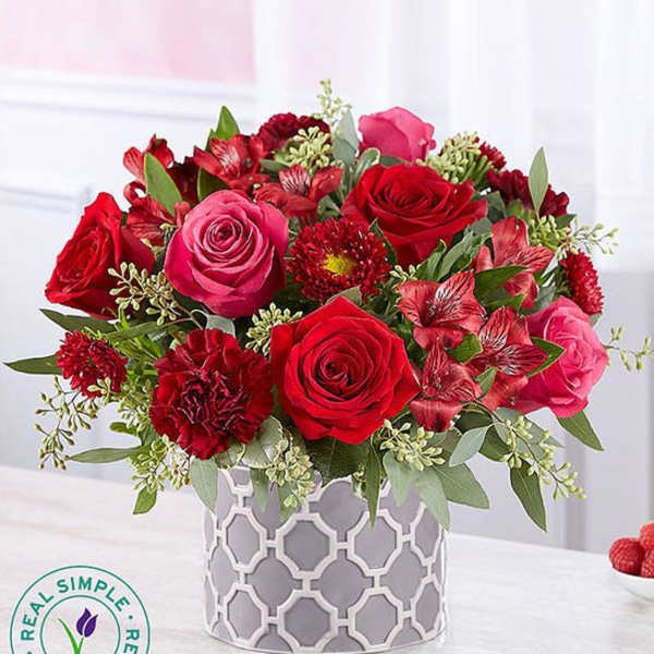 Red and pink rose bouquet in a patterned gray vase