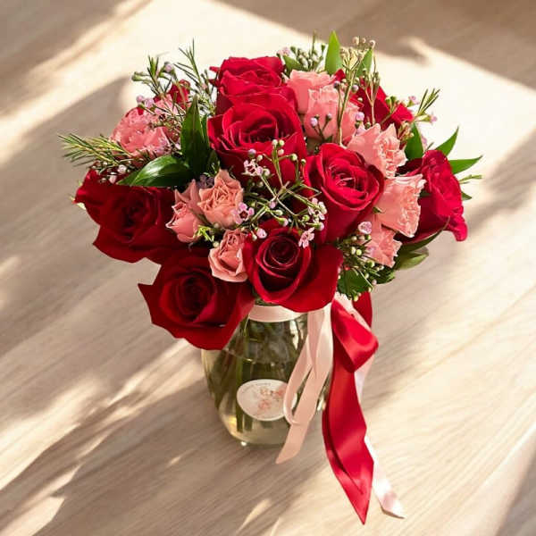 Bouquet of red and pink roses in a glass vase with ribbon