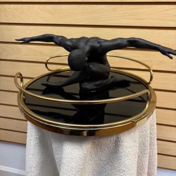 Black sculptural figure on a round mirrored table with gold rails