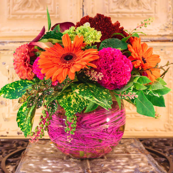 Bright mixed flower arrangement in a pink glass vase