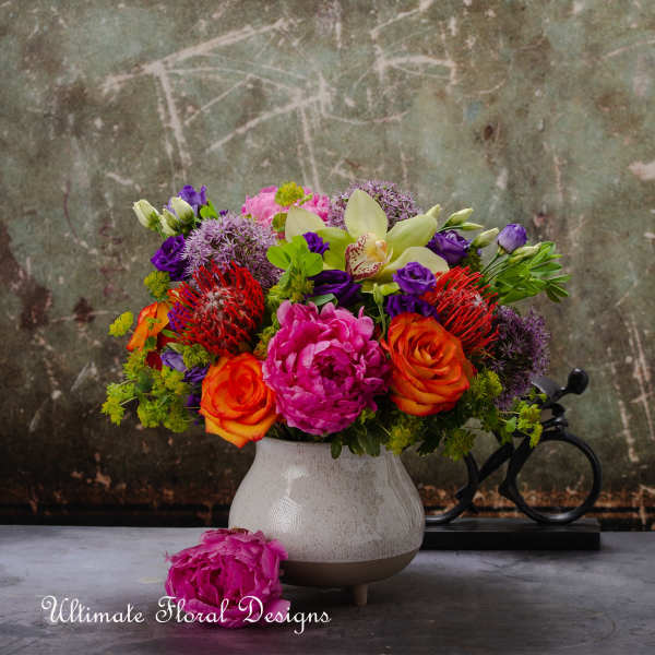 Colorful mixed bouquet in a white vase with roses and orchids