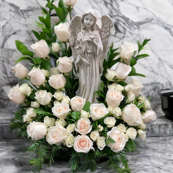 White roses arranged around a stone angel statue