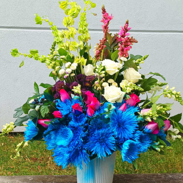Bright mixed bouquet in a blue vase with blue, pink, white, and green flowers