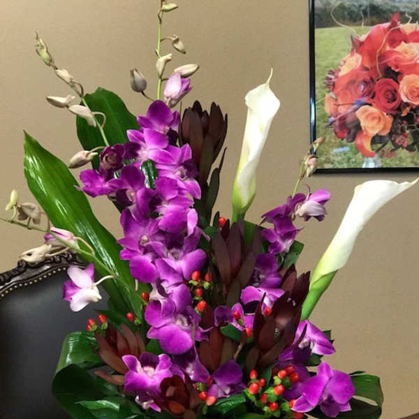 Purple orchids and white calla lilies in a black rectangular vase