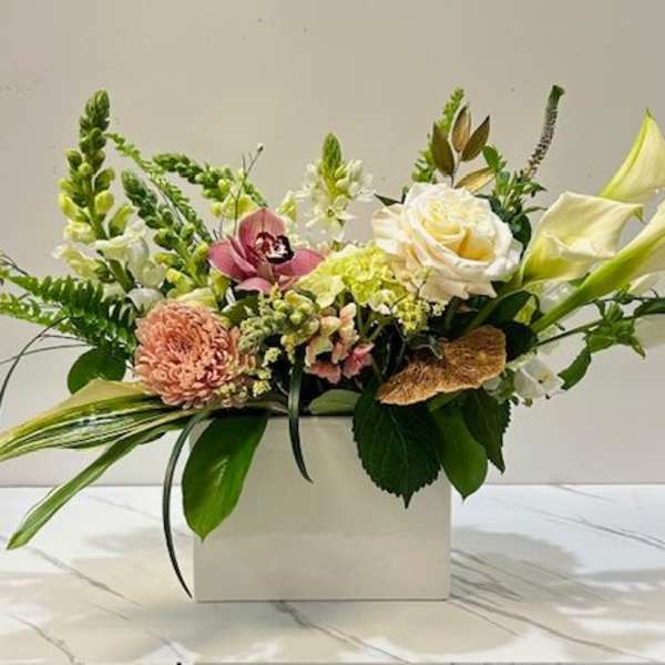 Mixed floral arrangement in a white rectangular box with pale lilies and roses