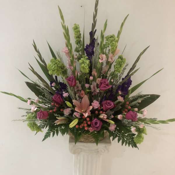 Tall floral arrangement with pink and purple roses in a basket