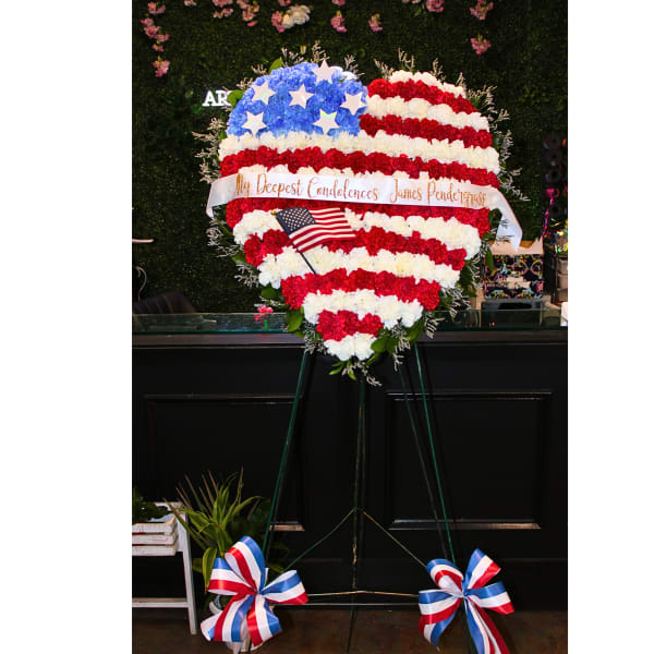 Heart-shaped red, white, and blue floral tribute on an easel with a ribbon