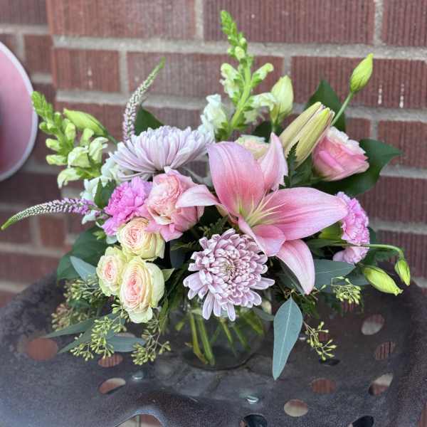 Pink lilies and pastel roses in a glass vase