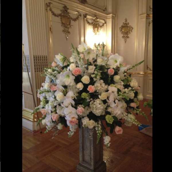 Large white and blush floral arrangement on a pedestal stand