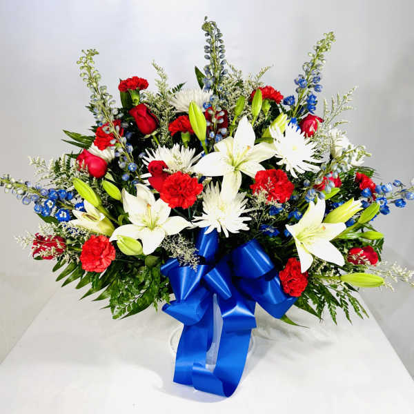 Red and white floral arrangement with a blue ribbon in a clear vase