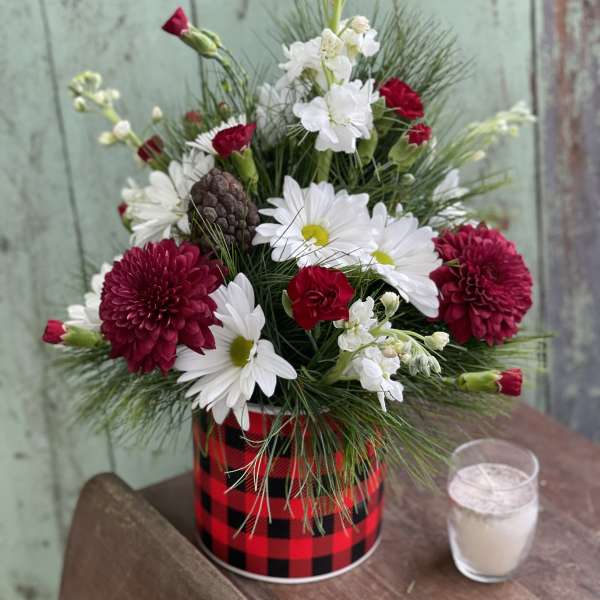 Red and white flower arrangement in a plaid tin container