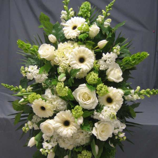 White floral standing spray with roses, gerbera daisies, and greenery