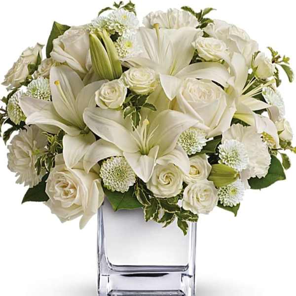 White lilies and roses arranged in a clear glass vase
