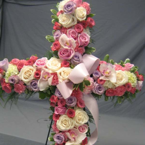 Cross-shaped floral arrangement with roses and orchids on a stand