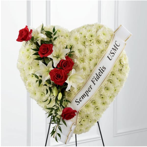 Heart-shaped funeral wreath with red roses and white lilies on a stand