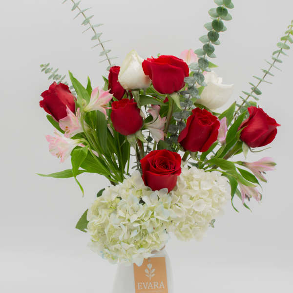 Red and white roses with pale pink alstroemeria in a white vase