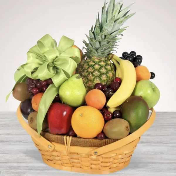Fruit basket with pineapple, bananas, grapes, and assorted fruit in a wicker basket