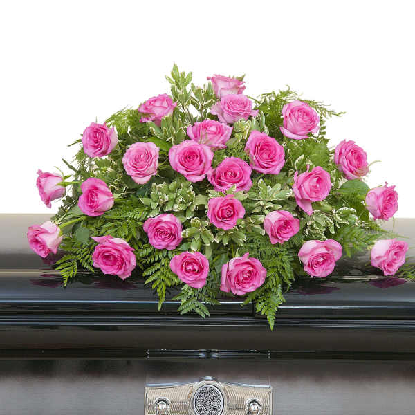 Pink rose casket spray arranged on a dark metal casket