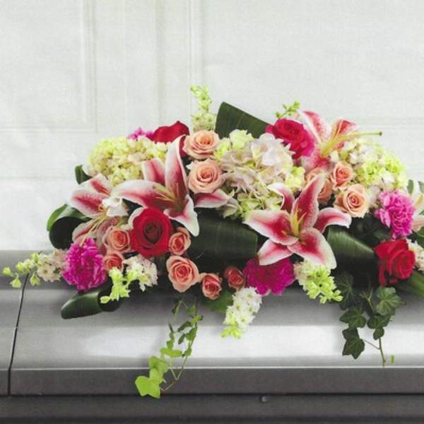 Casket spray with pink lilies, roses, and hydrangeas