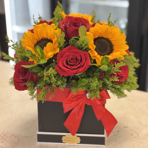 Red roses and sunflowers in a black box with a red ribbon