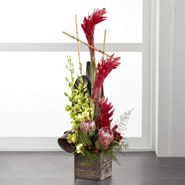 Tall tropical arrangement with red blooms in a wooden cube vase